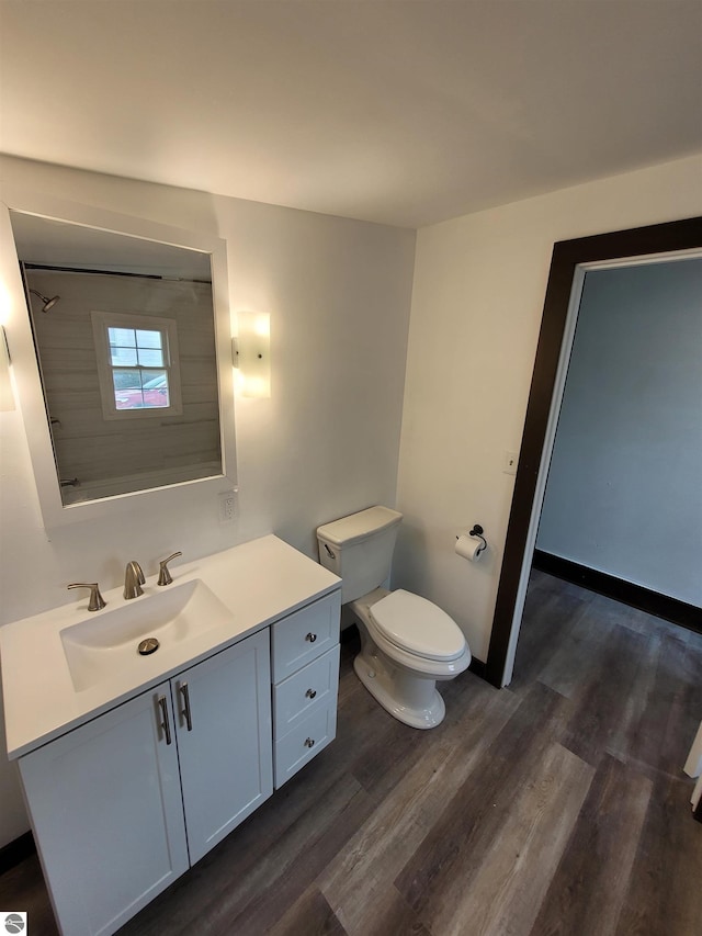 bathroom featuring hardwood / wood-style floors, vanity, toilet, and walk in shower