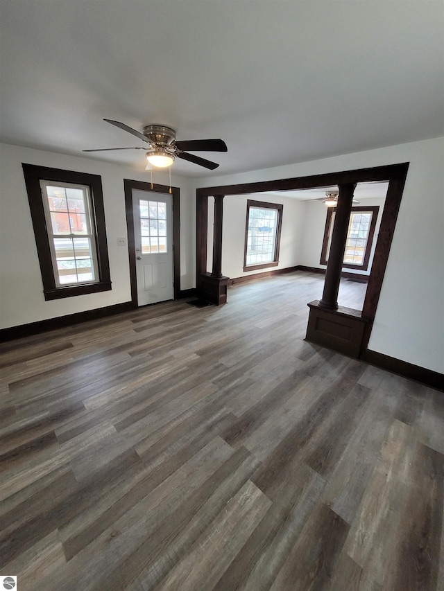 unfurnished living room featuring plenty of natural light and dark hardwood / wood-style flooring