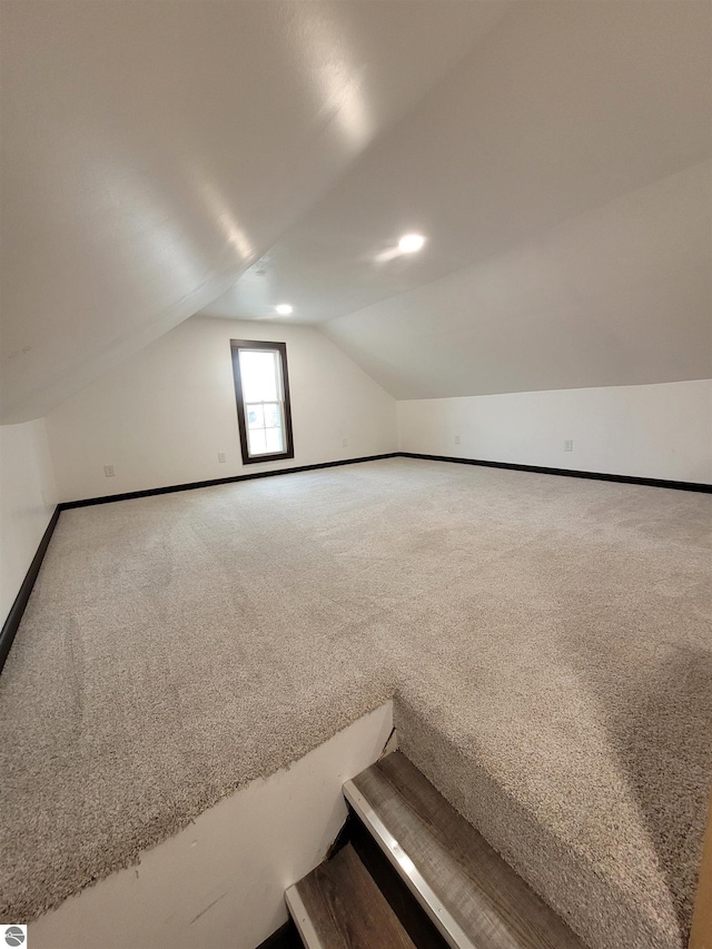 additional living space featuring carpet flooring and vaulted ceiling