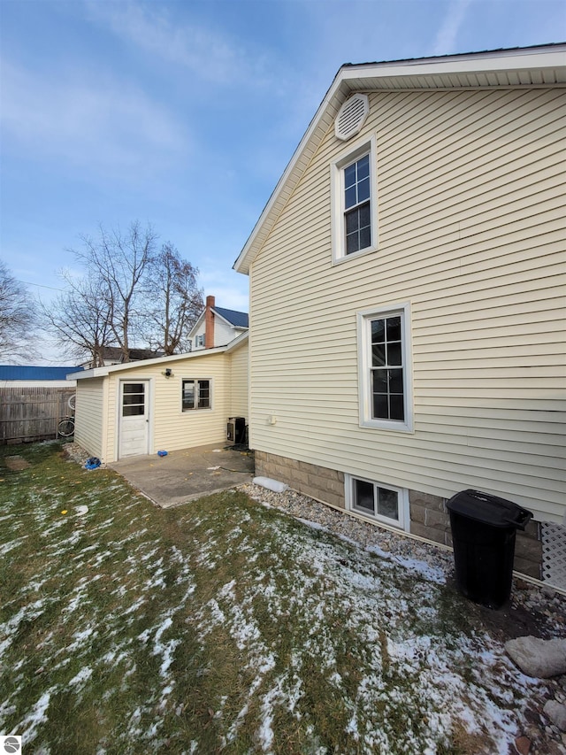 snow covered rear of property with cooling unit and a patio area