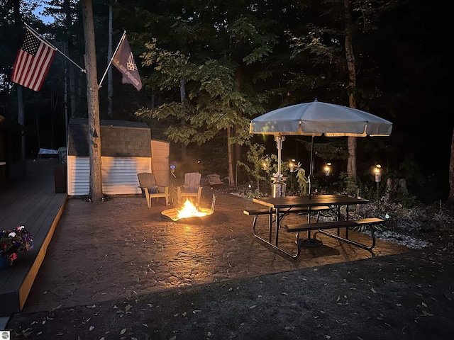 patio at twilight with a fire pit and a wooden deck