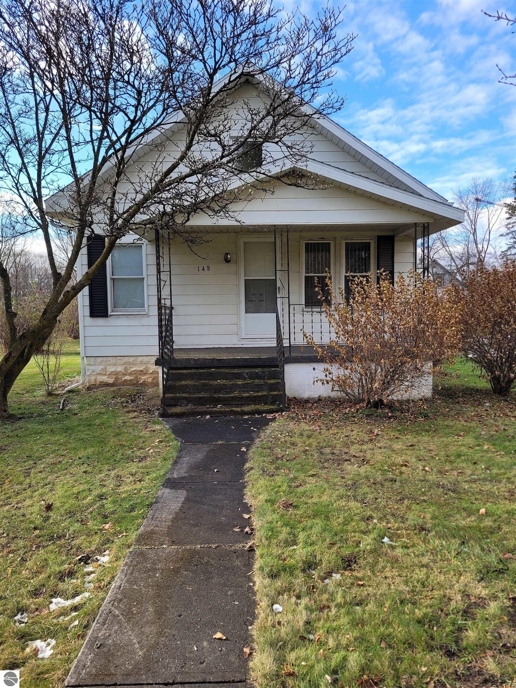 bungalow featuring covered porch and a front lawn