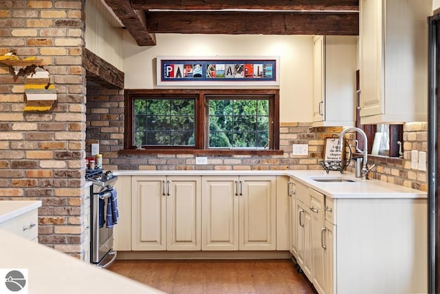 kitchen with beam ceiling, gas range, sink, and light wood-type flooring