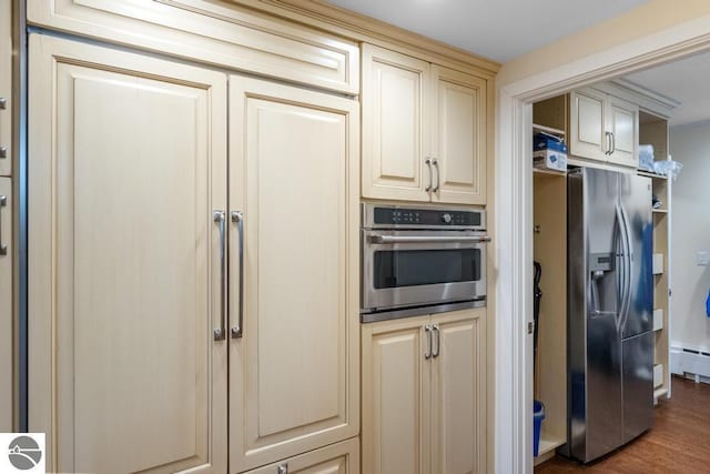 kitchen with cream cabinets, dark hardwood / wood-style flooring, stainless steel appliances, and a baseboard radiator