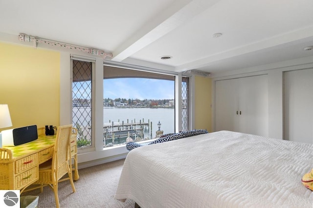 bedroom featuring beam ceiling, carpet floors, a water view, and multiple windows