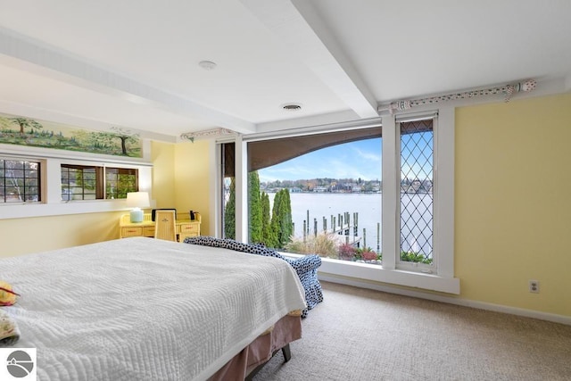 bedroom with beam ceiling, carpet floors, a water view, and multiple windows