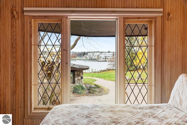 bedroom featuring multiple windows, wooden walls, and a water view