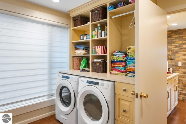 clothes washing area with dark hardwood / wood-style flooring, washing machine and dryer, and brick wall