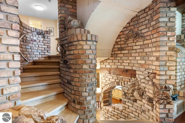 interior space with hardwood / wood-style floors, brick wall, and vaulted ceiling