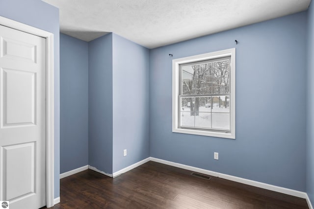 empty room featuring dark hardwood / wood-style floors and a textured ceiling