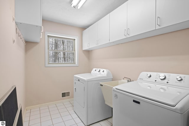 laundry room with washer and dryer, cabinets, and light tile patterned flooring