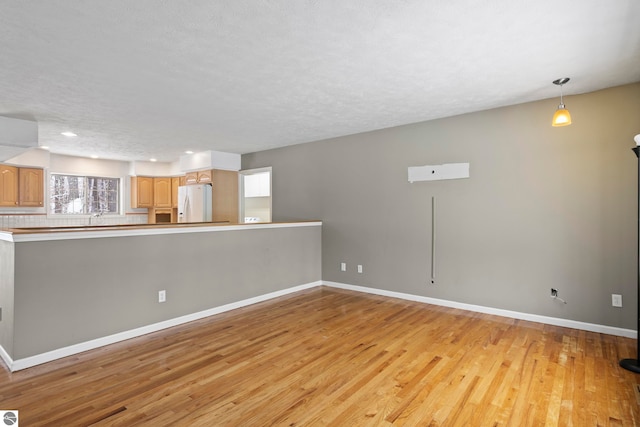 unfurnished living room with a textured ceiling and light hardwood / wood-style flooring