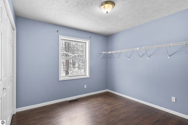 empty room with a textured ceiling and dark hardwood / wood-style floors