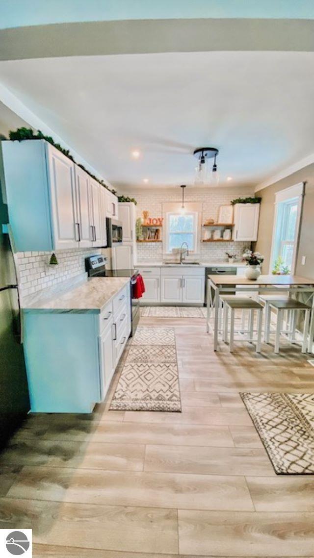 kitchen featuring decorative backsplash, light hardwood / wood-style flooring, white cabinetry, and sink