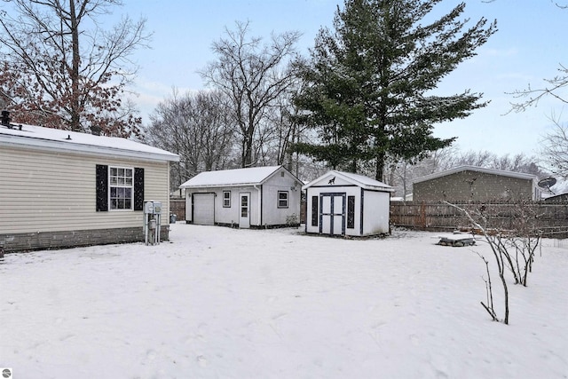 yard covered in snow with a garage and a storage shed