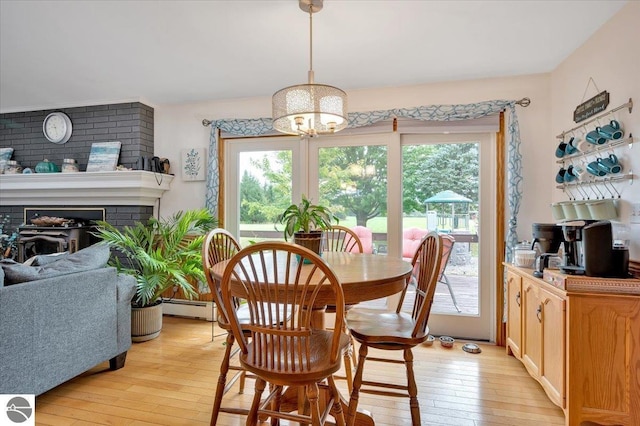 dining space with a baseboard radiator, a fireplace, and light hardwood / wood-style floors