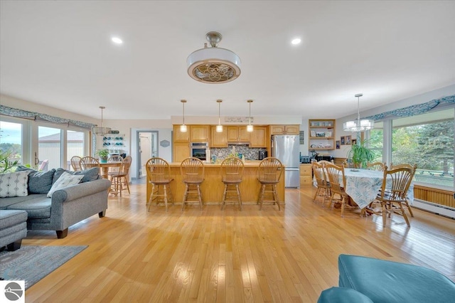 living room with an inviting chandelier, a wealth of natural light, and light wood-type flooring