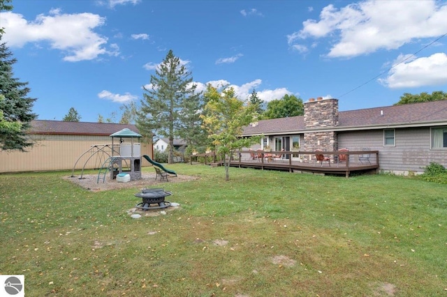 view of yard with a fire pit, a playground, and a deck