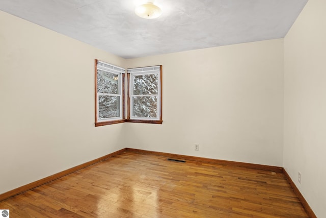 unfurnished room featuring light wood-style flooring, visible vents, and baseboards