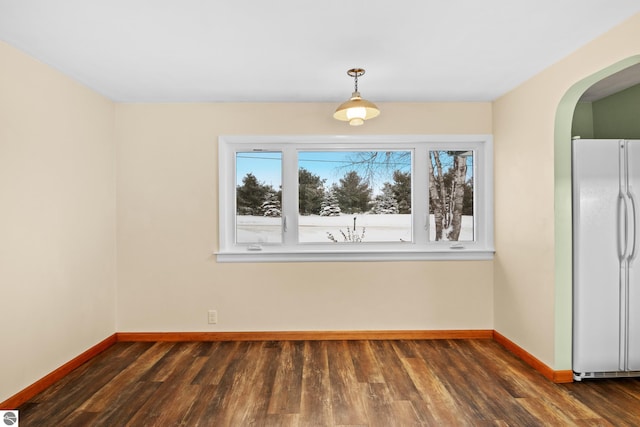 unfurnished dining area with a healthy amount of sunlight, dark wood finished floors, and baseboards