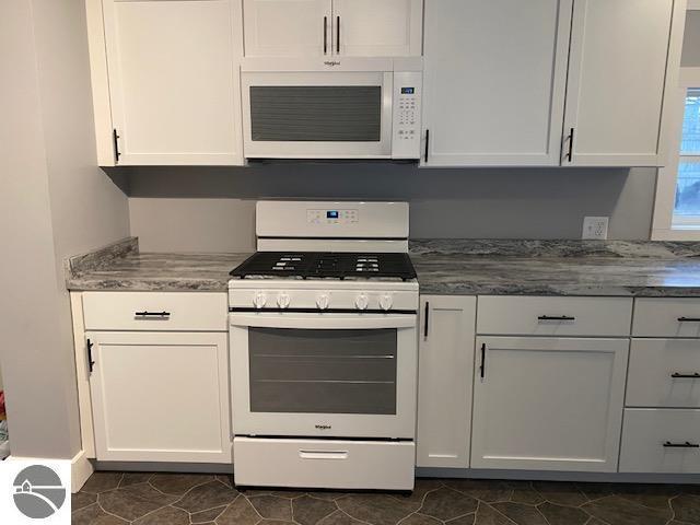 kitchen featuring white cabinets, white appliances, and dark tile patterned floors