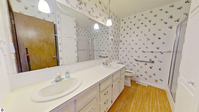 bathroom featuring hardwood / wood-style floors, vanity, a shower with shower door, and toilet