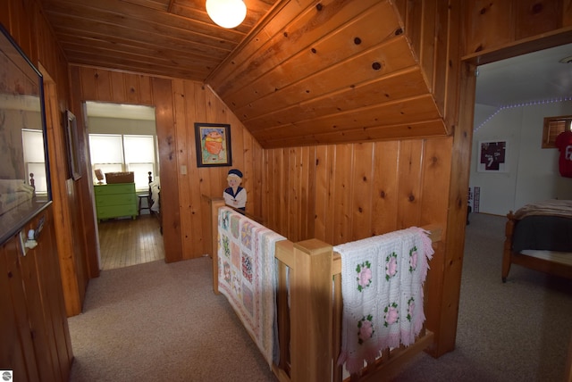 interior space featuring wood ceiling, wood walls, light colored carpet, and vaulted ceiling