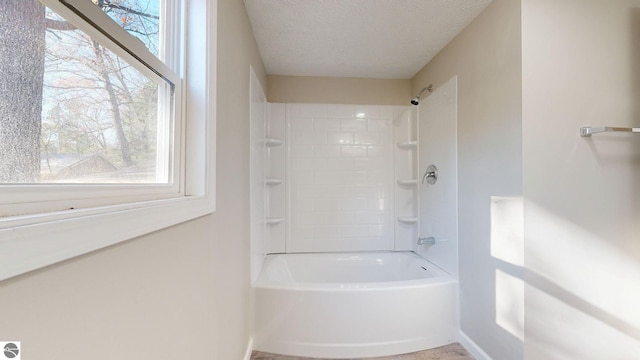 bathroom with tiled shower / bath combo and a textured ceiling