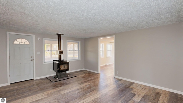 entryway featuring a wood stove, wood-type flooring, and a textured ceiling