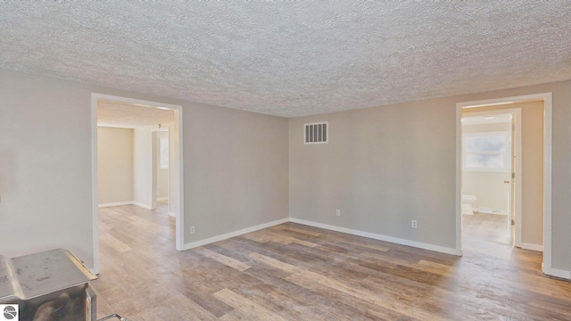 empty room with a textured ceiling and light wood-type flooring