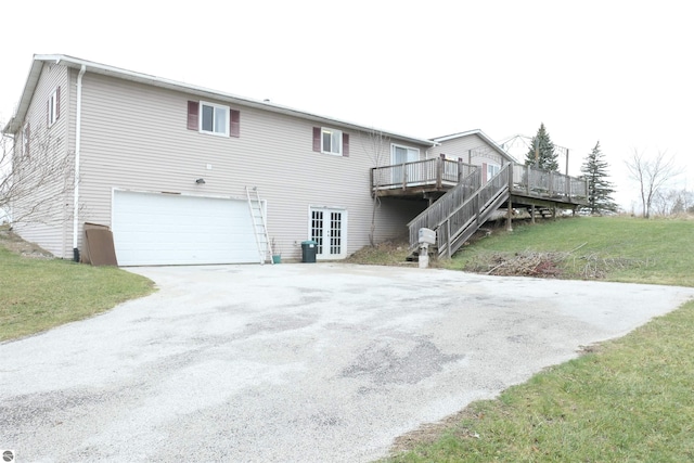 back of property featuring a lawn, a garage, and a deck