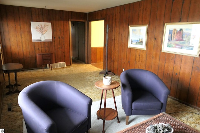 sitting room featuring carpet flooring and wood walls