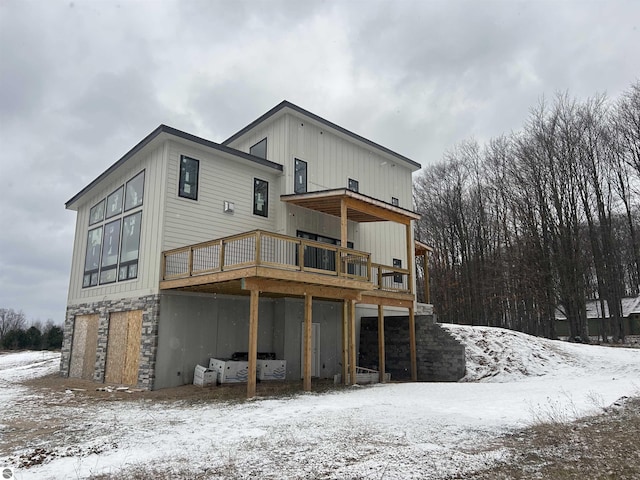 snow covered rear of property with a wooden deck