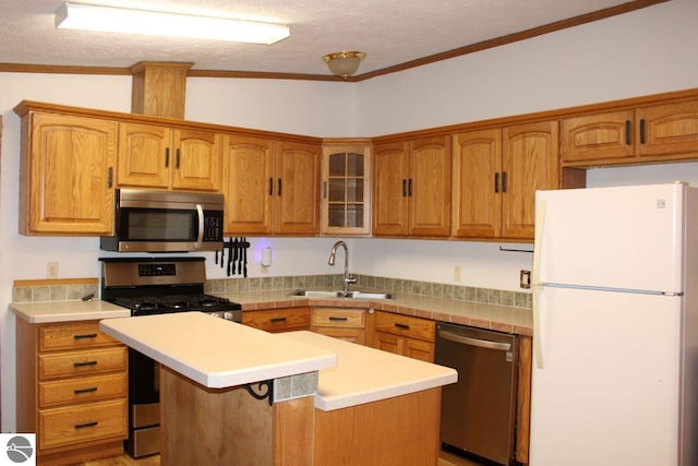 kitchen with glass insert cabinets, a sink, stainless steel appliances, light countertops, and a center island