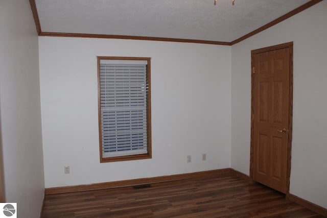 spare room with dark wood-style flooring, ornamental molding, and baseboards