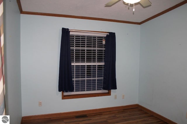 empty room with wood finished floors, ceiling fan, crown molding, and visible vents