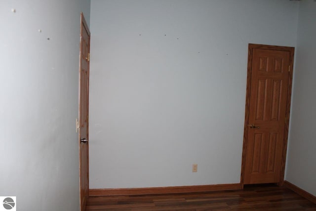 spare room with dark wood finished floors and baseboards