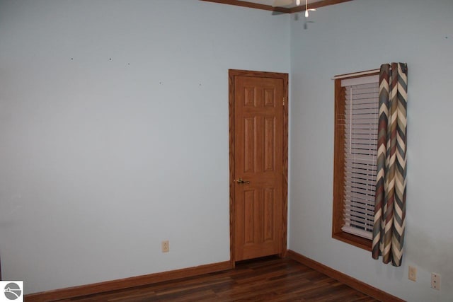 spare room with baseboards, ceiling fan, and dark wood-style flooring