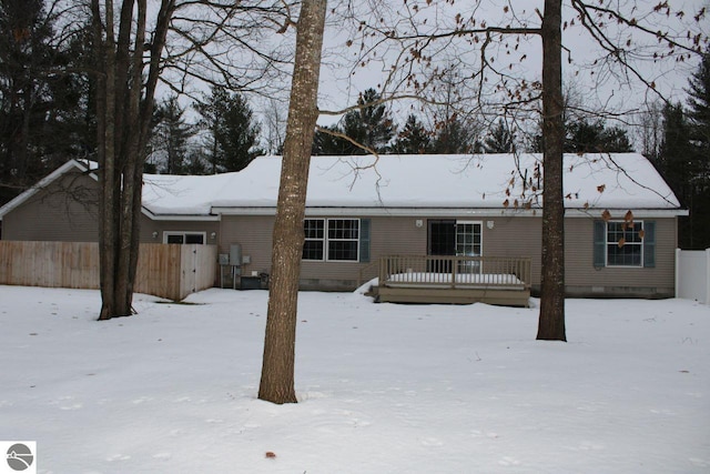 snow covered rear of property with a deck