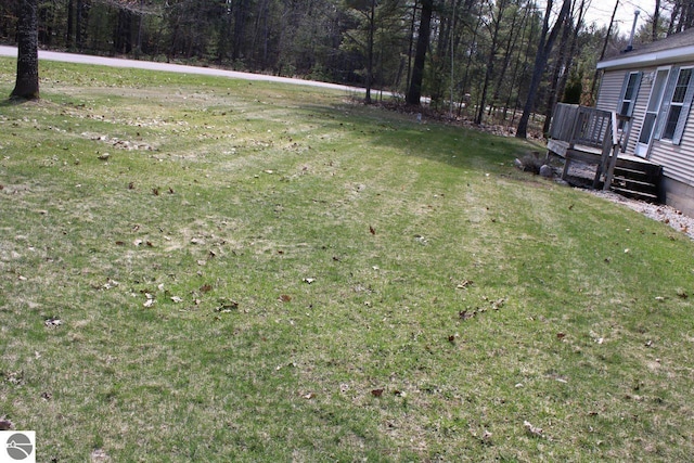 view of yard with a wooded view and a wooden deck