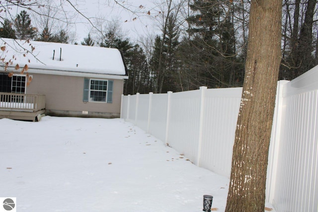snowy yard with a deck and fence
