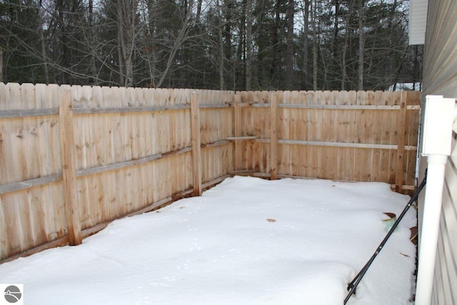 snowy yard with a fenced backyard