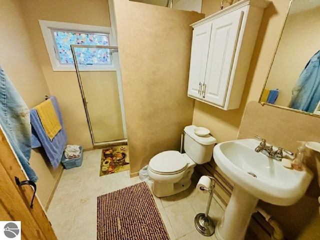 bathroom with tile patterned flooring, toilet, and a shower with door