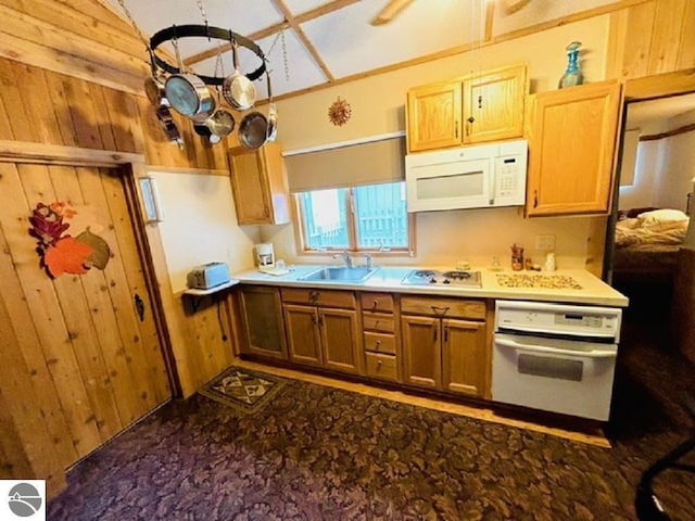 kitchen featuring wood walls, white appliances, and sink