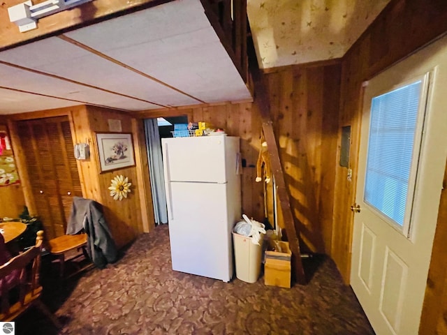 kitchen featuring white refrigerator and wooden walls