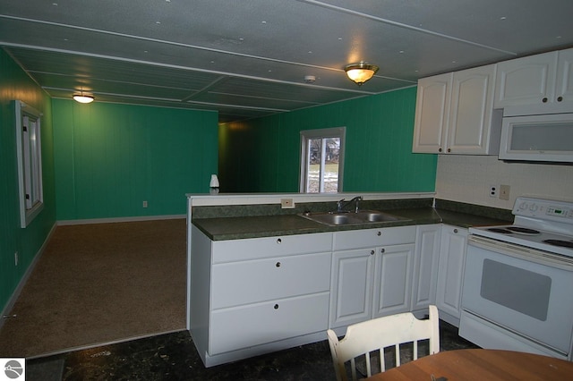 kitchen featuring kitchen peninsula, dark carpet, white appliances, sink, and white cabinets