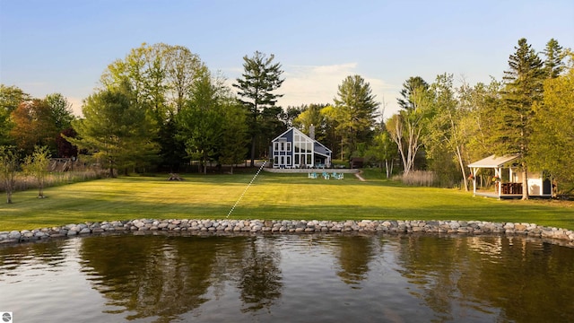 back of house with a lawn and a water view