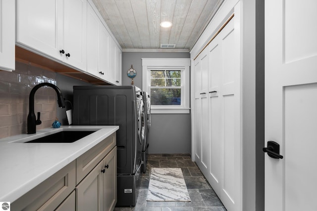 washroom with cabinets, ornamental molding, wood ceiling, sink, and separate washer and dryer