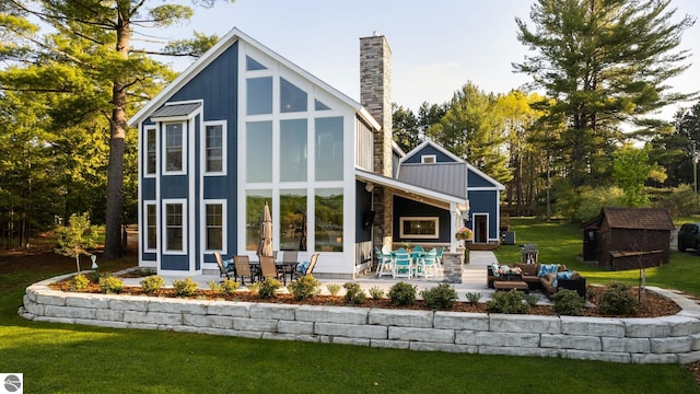 rear view of house featuring an outdoor living space, a patio area, and a storage shed