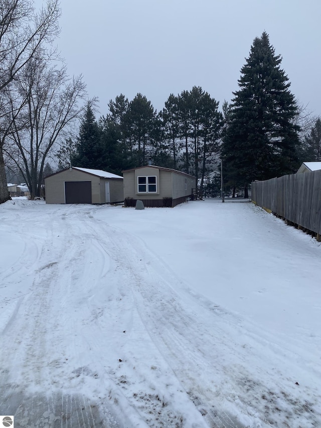 yard layered in snow with an outbuilding and a garage